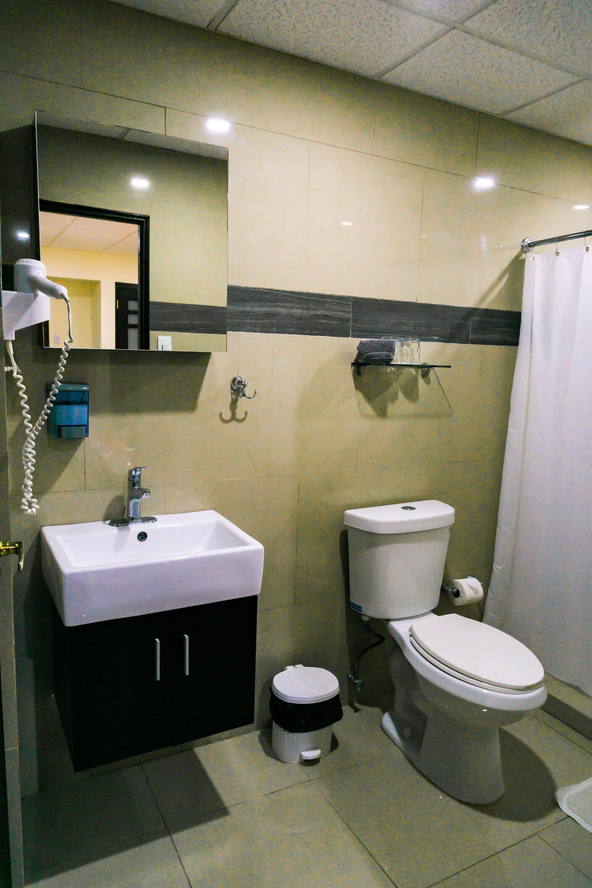 A standard bathroom with a sink, toilet, and shower curtain.