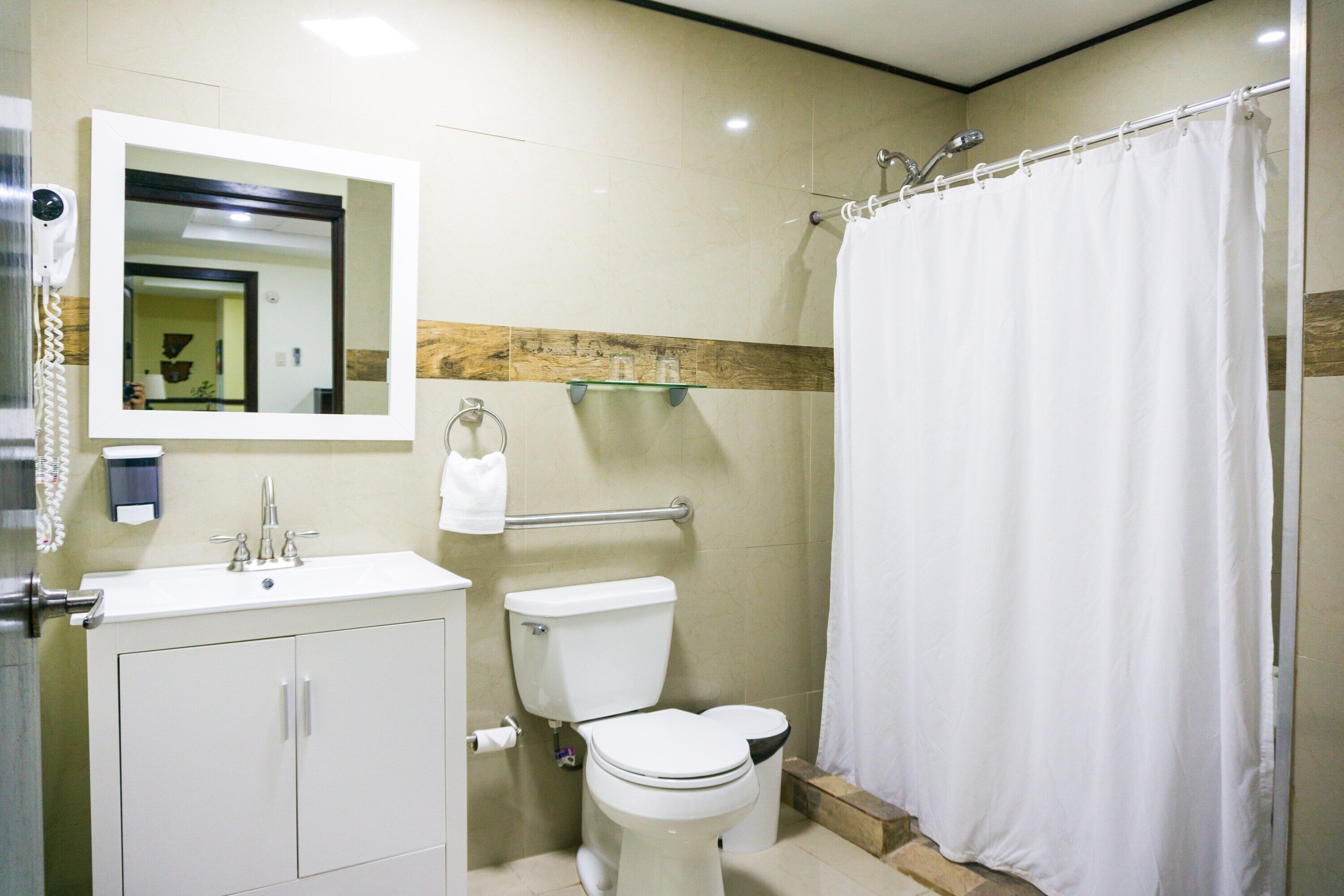 A bathroom with a toilet, sink, mirror, and shower curtain.