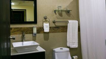 A bathroom with a white sink, a toilet, a mirror, and a shower curtain.