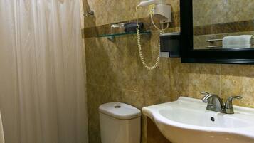 A bathroom with a toilet, sink, mirror, shower curtain, and a towel rack.