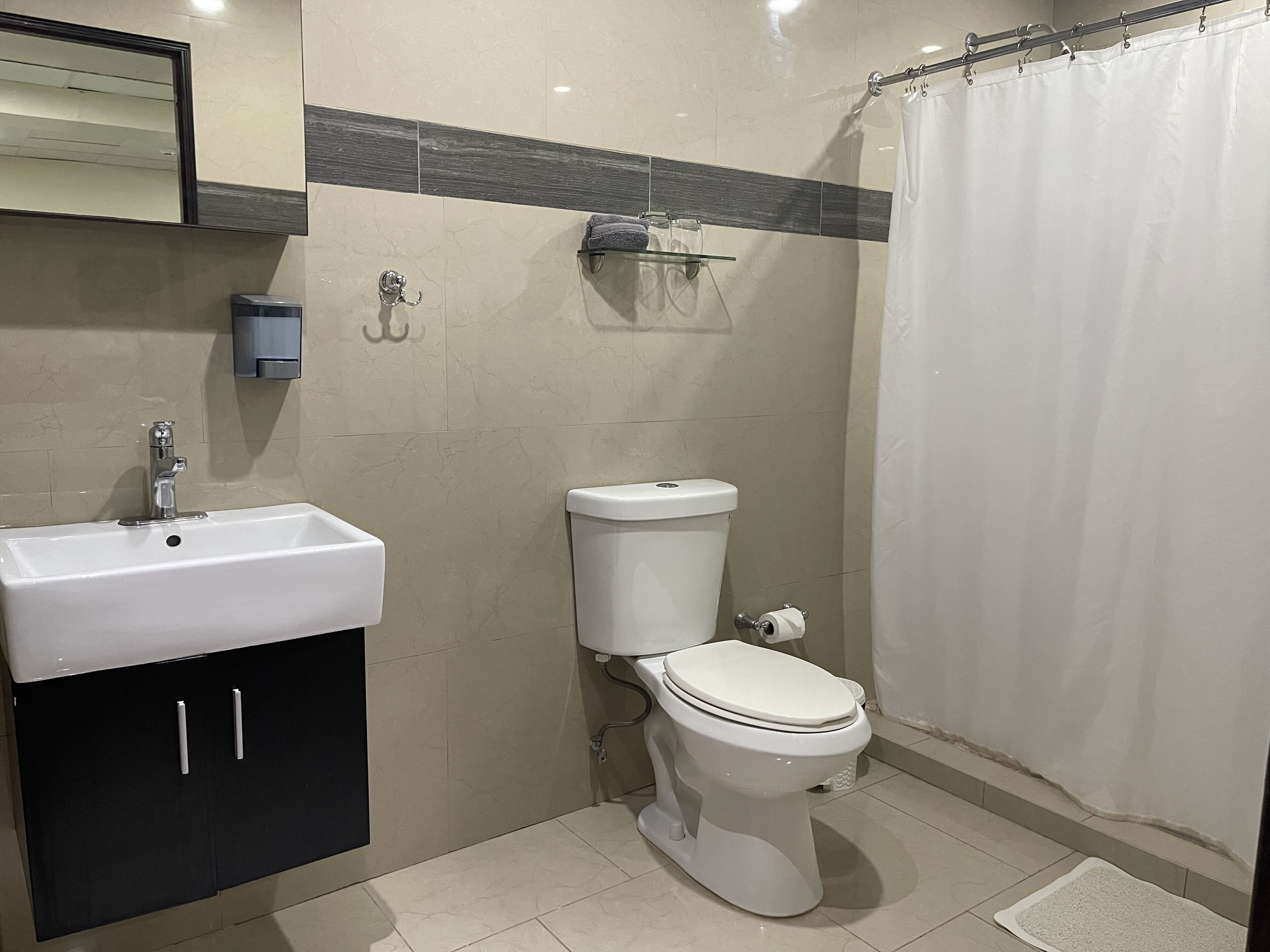 Un baño con lavamanos, inodoro y cortina de ducha.