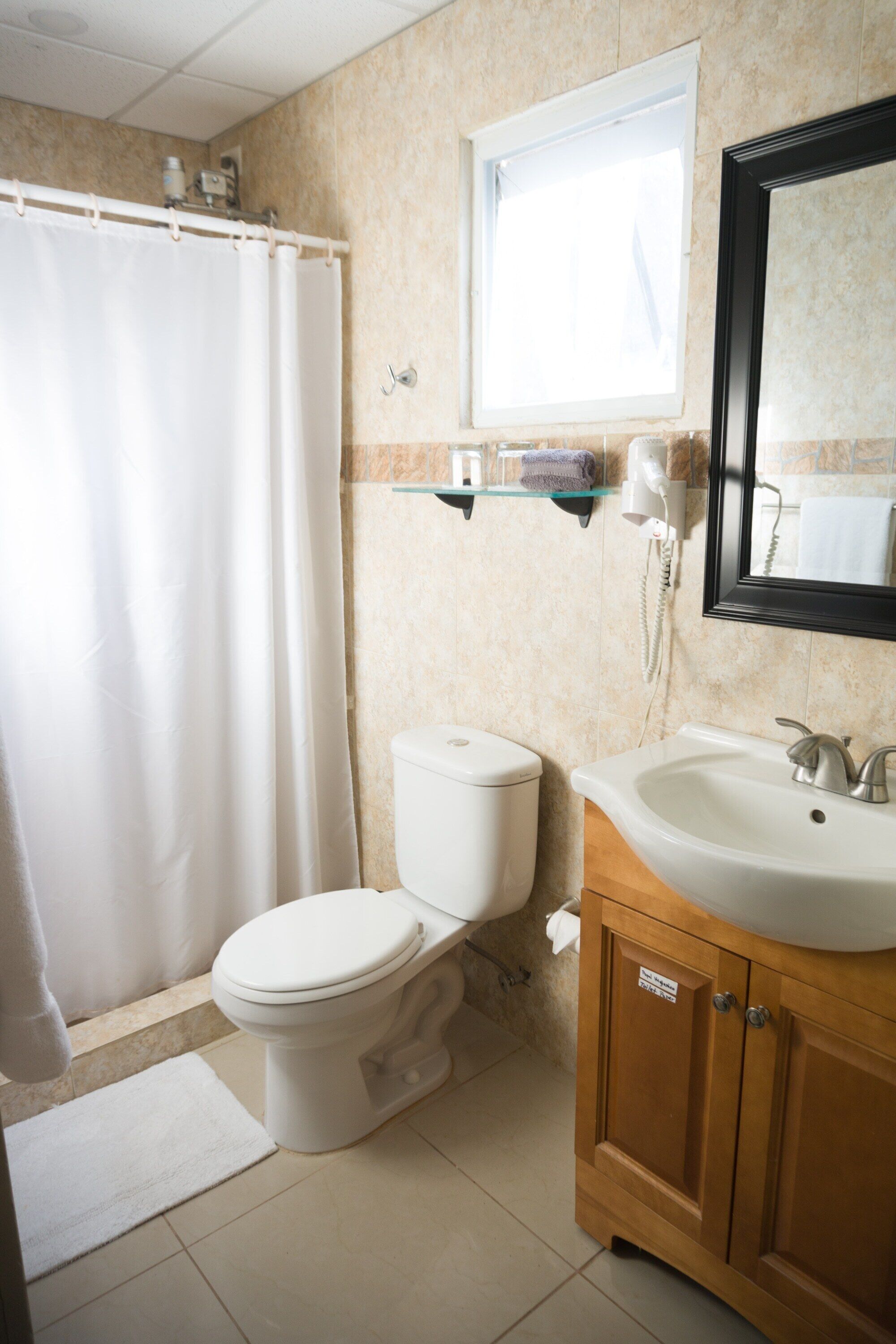 Un baño con inodoro, lavamanos y cortina de ducha.