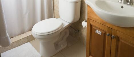 Un baño con inodoro, lavamanos y cortina de ducha.