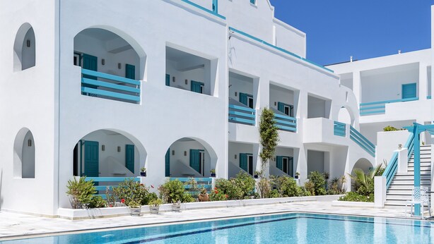 A modern white building with a pool, featuring balconies and arched windows. - Santellini Hotel (Santorini)