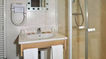 Une salle de bain moderne avec une douche à parois de verre, un lavabo avec un miroir au-dessus et un porte-serviettes.