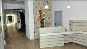 A modern reception area with a stone accent wall, a staircase leading to a balcony, and a minimalist design. - Hôtel Atlantic (La Rochelle)
