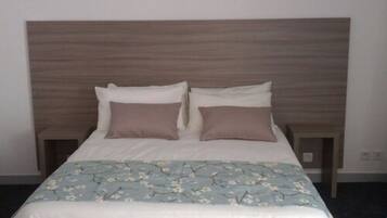 Una cama bien hecha con una colcha estampada de flores y dos almohadas.