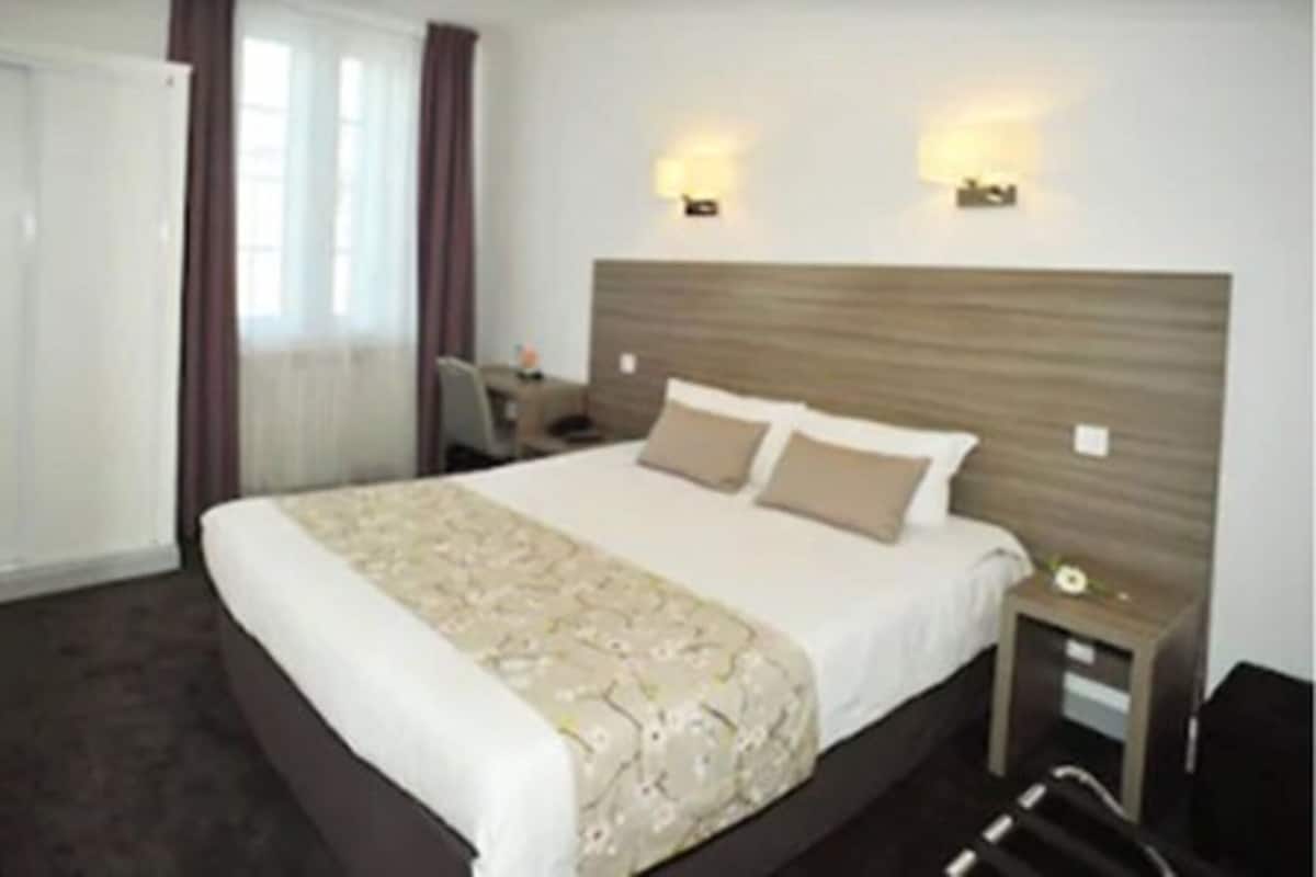 Una habitació d'hotel amb un llit gran, dues làmpades de nit, un escriptori i una cadira.