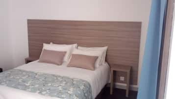 Un lit bien fait, recouvert d’une couvre-lit à motifs floraux et agrémenté de deux oreillers.