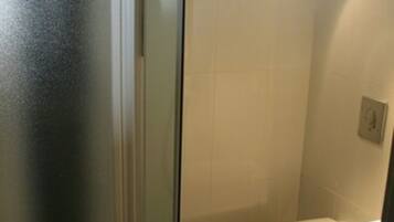 Une salle de bain avec une douche à parois de verre, des toilettes blanches et un lavabo blanc.