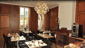 Un espace repas agrémenté de lambris en bois, d’une cheminée et d’un lustre moderne.