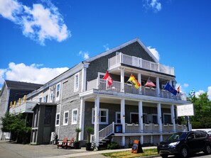 A two-story building with a balcony, multiple flags, and a sign indicating it is a hotel and coffee shop.
