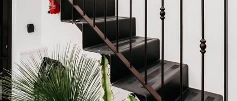 Un escalier avec des rampes et des marches noires, menant à l’étage supérieur.