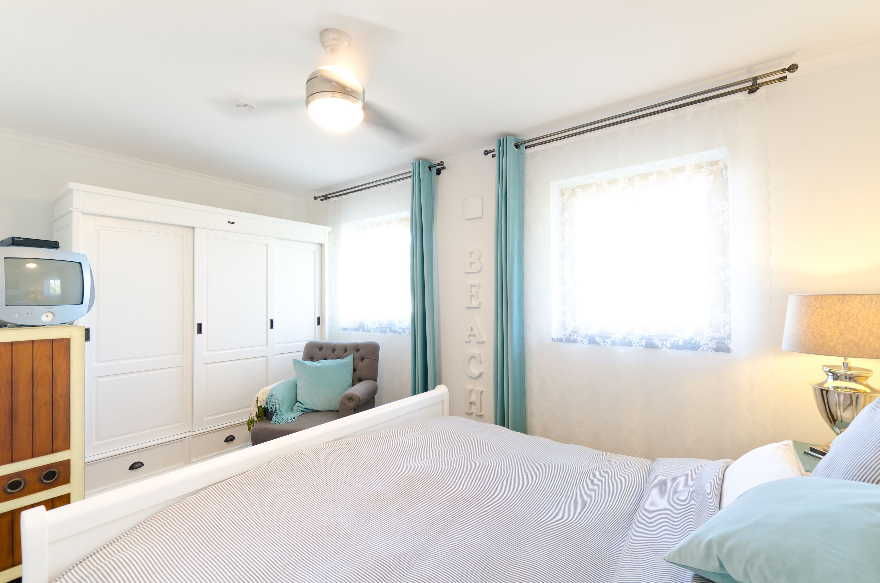 A bedroom with a bed, a chair, a TV, and a wardrobe.