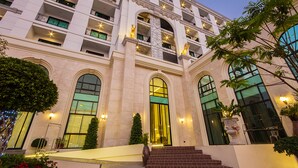 A multi-story hotel with a grand entrance, large arched windows, and a well-lit facade. - SN Plus Hotel - SHA Plus (Pattaya)