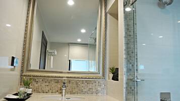 A bathroom with a large mirror, a sink, and a shower area.