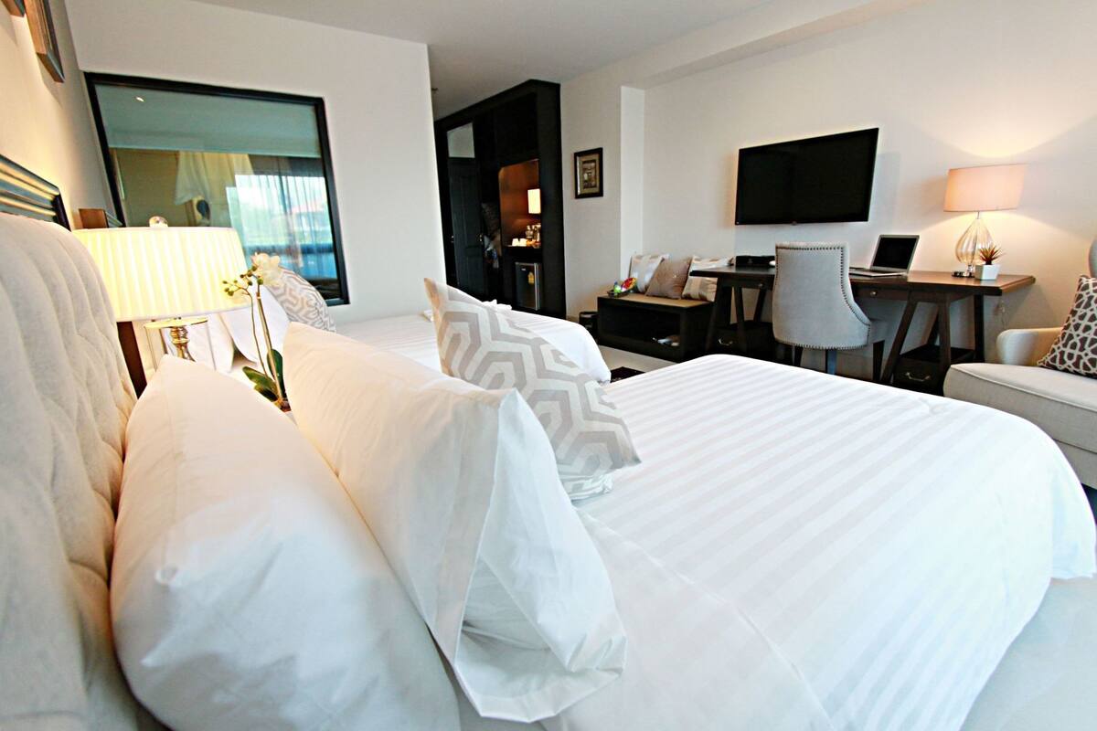 Una habitación de hotel con una cama grande, un escritorio, una silla, un televisor y una lámpara.