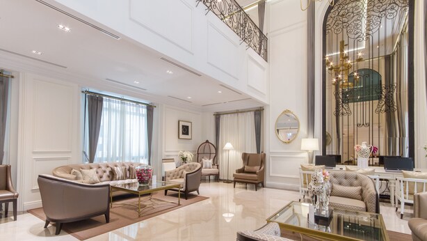 A spacious living room with a high ceiling, elegant furniture, and a large decorative mirror. - SN Plus Hotel - SHA Plus (Pattaya)