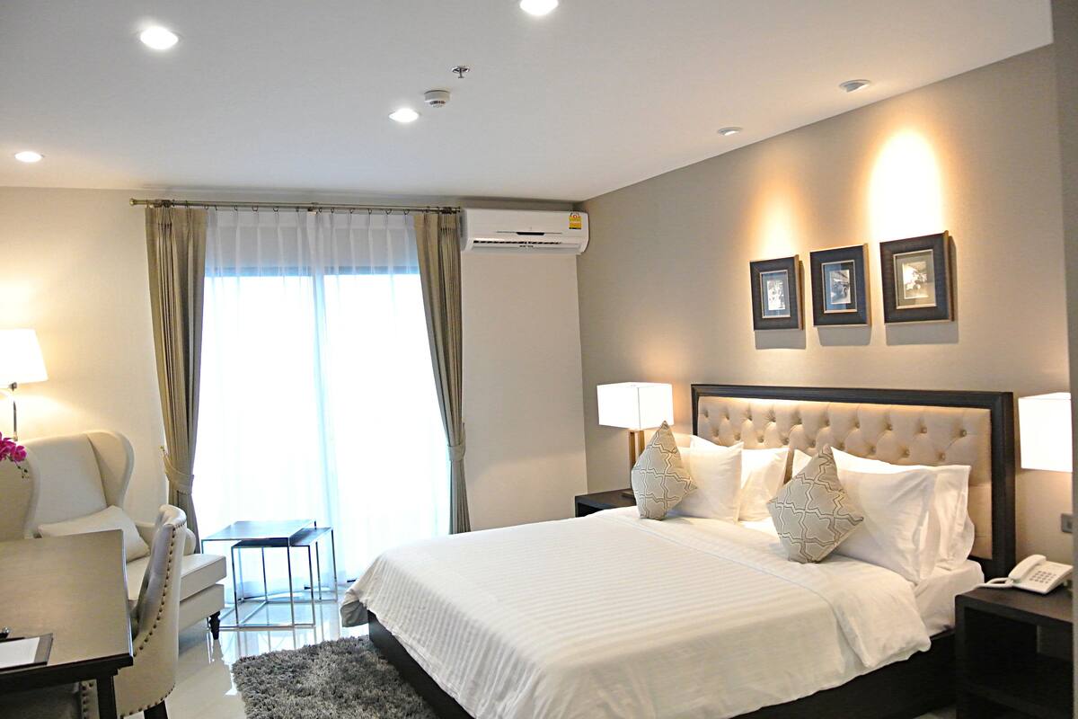 Una habitación de hotel con una cama grande, un escritorio, una silla y una mesa de comedor.