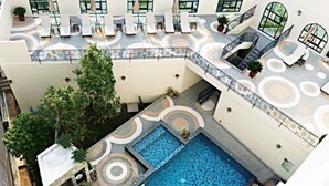 An aerial view of a hotel with a central swimming pool, outdoor seating areas, and a rooftop terrace. - SN Plus Hotel - SHA Plus (Pattaya)