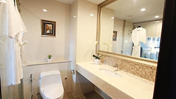 A modern bathroom with a large mirror, a toilet, a sink, and a shower.
