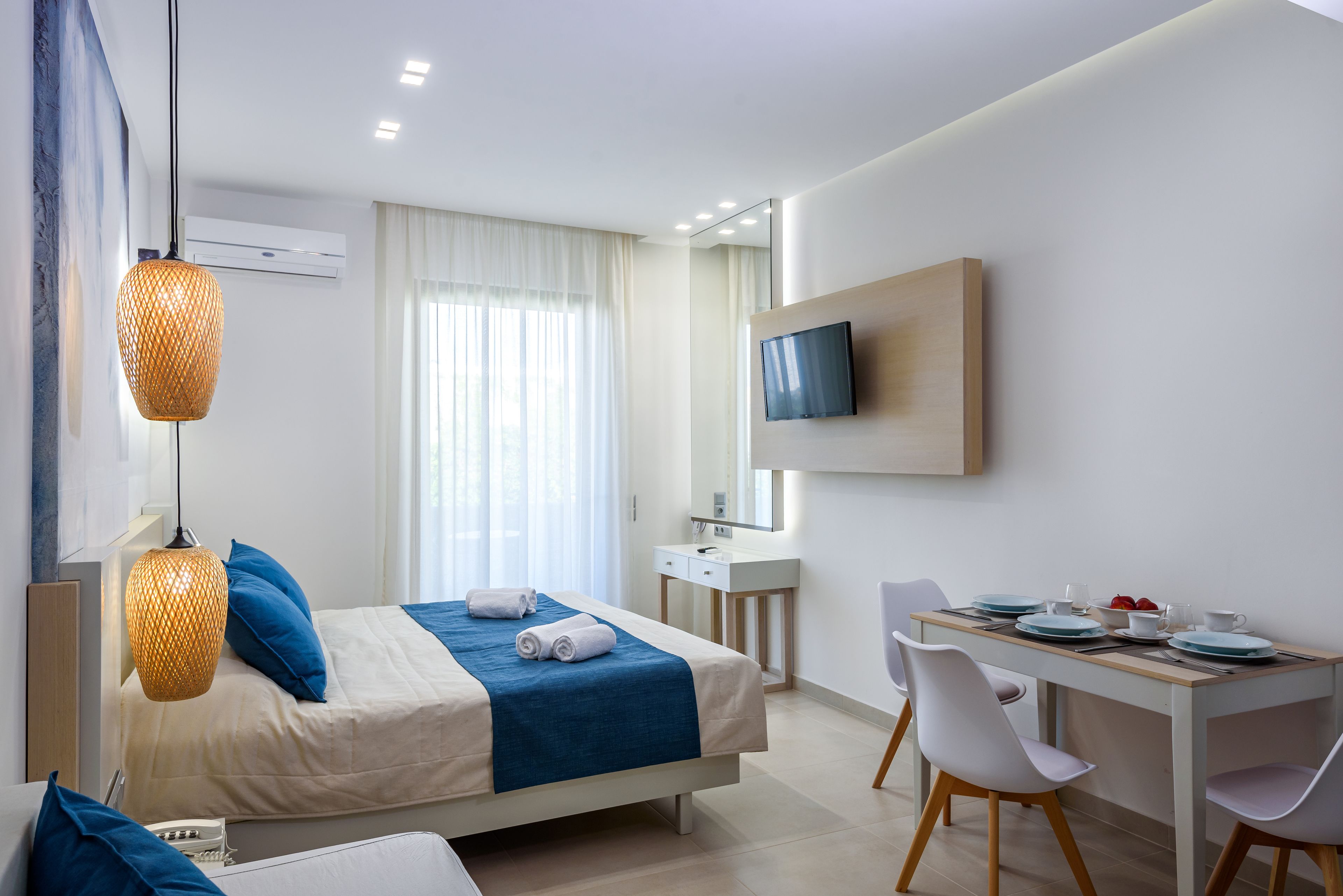 Ein modernes Hotelzimmer mit Bett, Schreibtisch, Fernseher und einem Fenster mit Vorhängen.