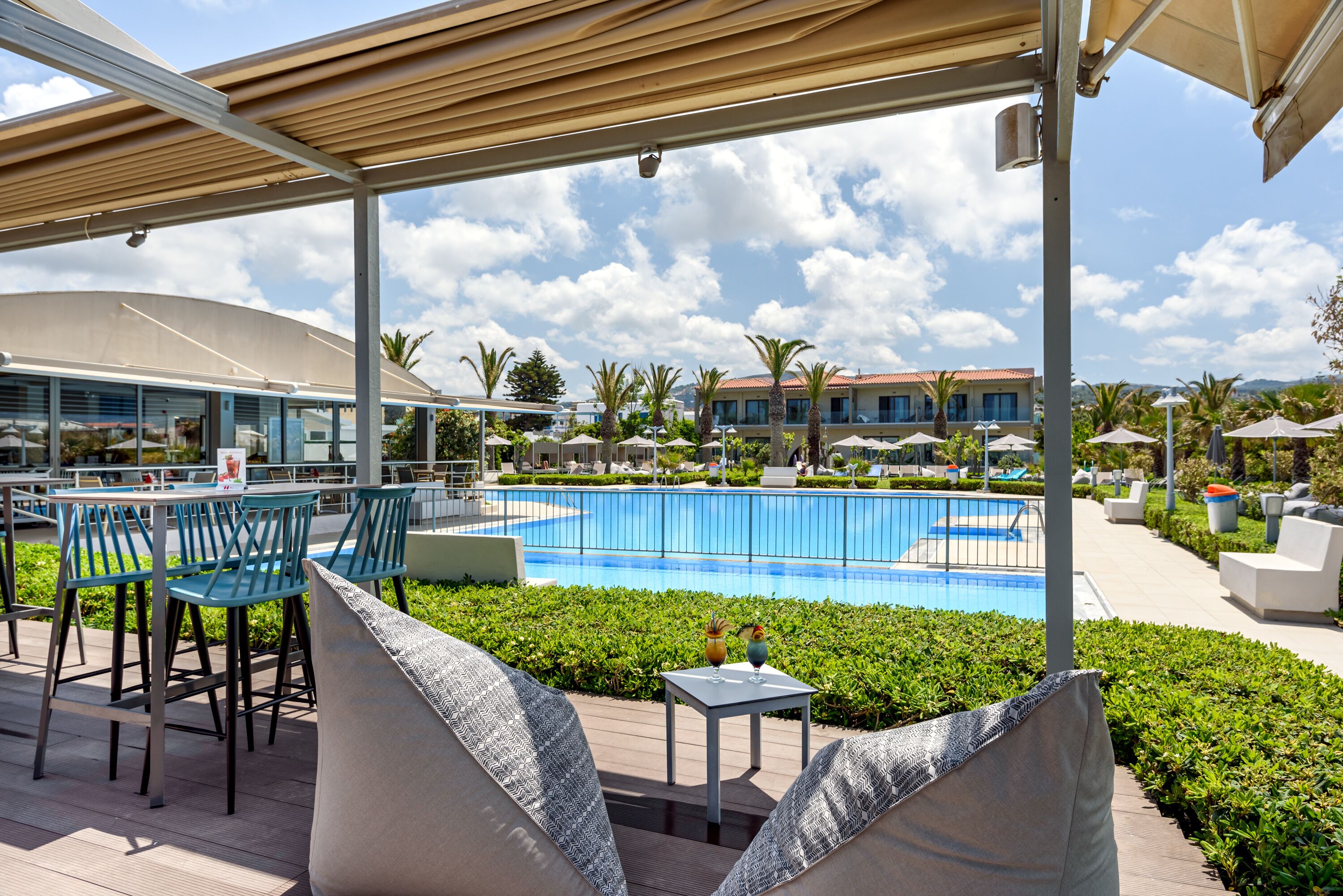 A poolside area with outdoor seating, a pool, and a building in the background.
