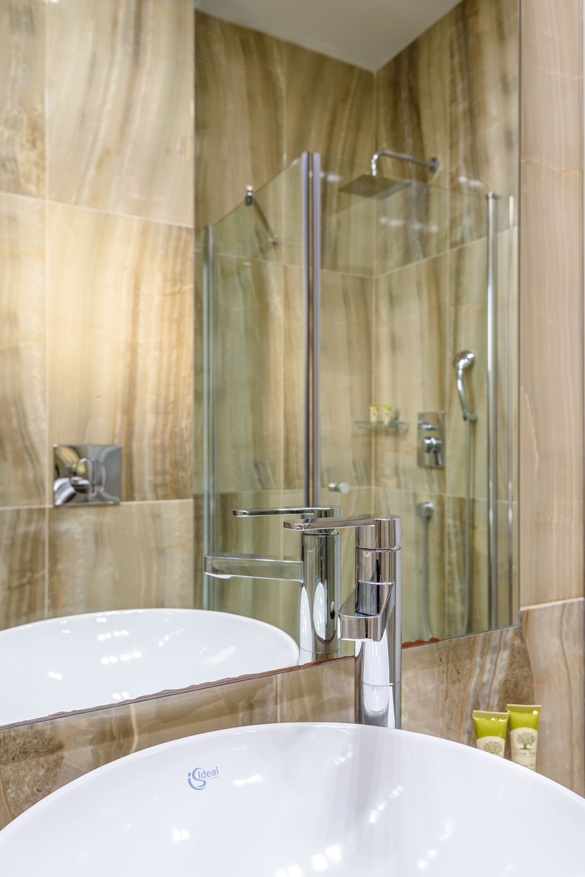 A bathroom with a large mirror, a white sink, and a glass-enclosed shower.
