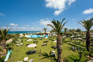 Una piscina al aire libre, sombrillas, sillones reclinables de piscina