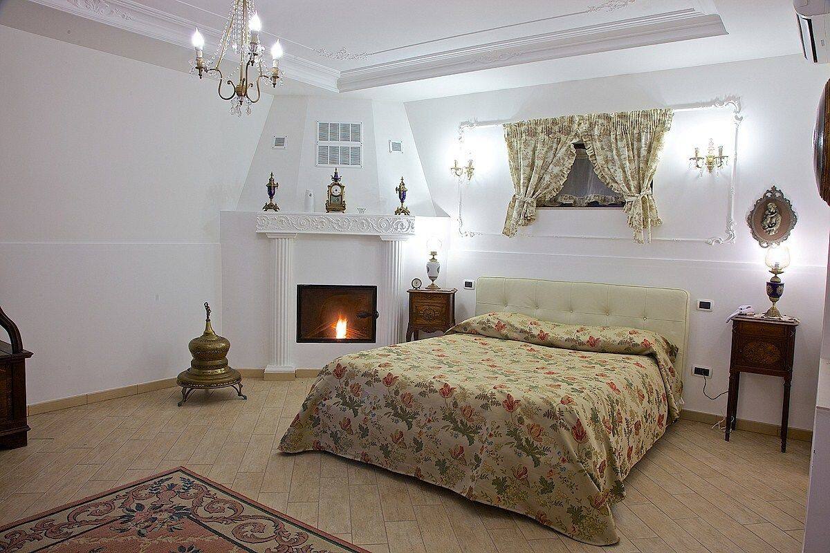 Un dormitorio con una cama grande, una chimenea y un candelabro.