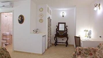 Una sala de estar con sofá, mesa de centro, mesita auxiliar con lámpara, espejo y un mueble bajo.
