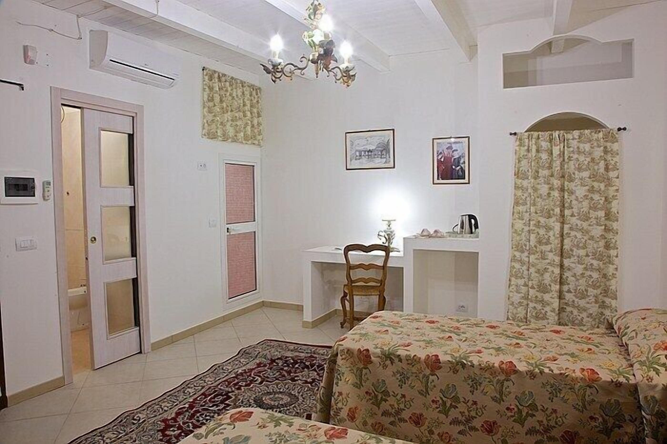 A bedroom with a bed, a desk, a chair, a radiator, and a door.