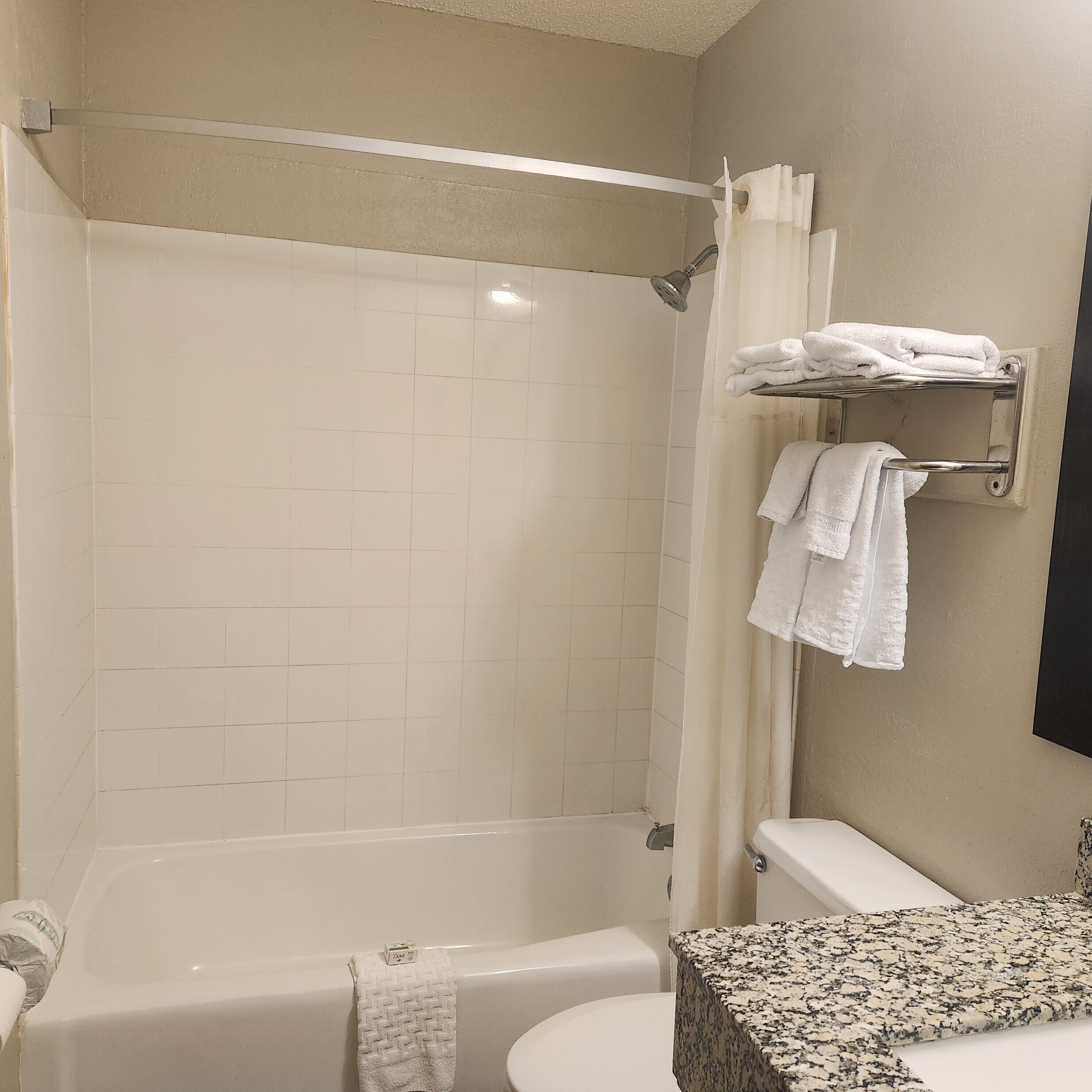 A bathroom with a bathtub, toilet, and a towel rack with towels.