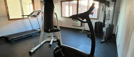 A gym with exercise equipment including a treadmill, elliptical, and weight machines.