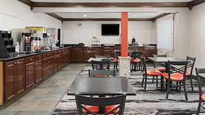 Una cocina amplia con electrodomésticos modernos, armarios de madera y un comedor con mesas y sillas.