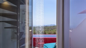 Un balcon avec une balustrade rouge, un coussin bleu et une vue sur un paysage verdoyant.
