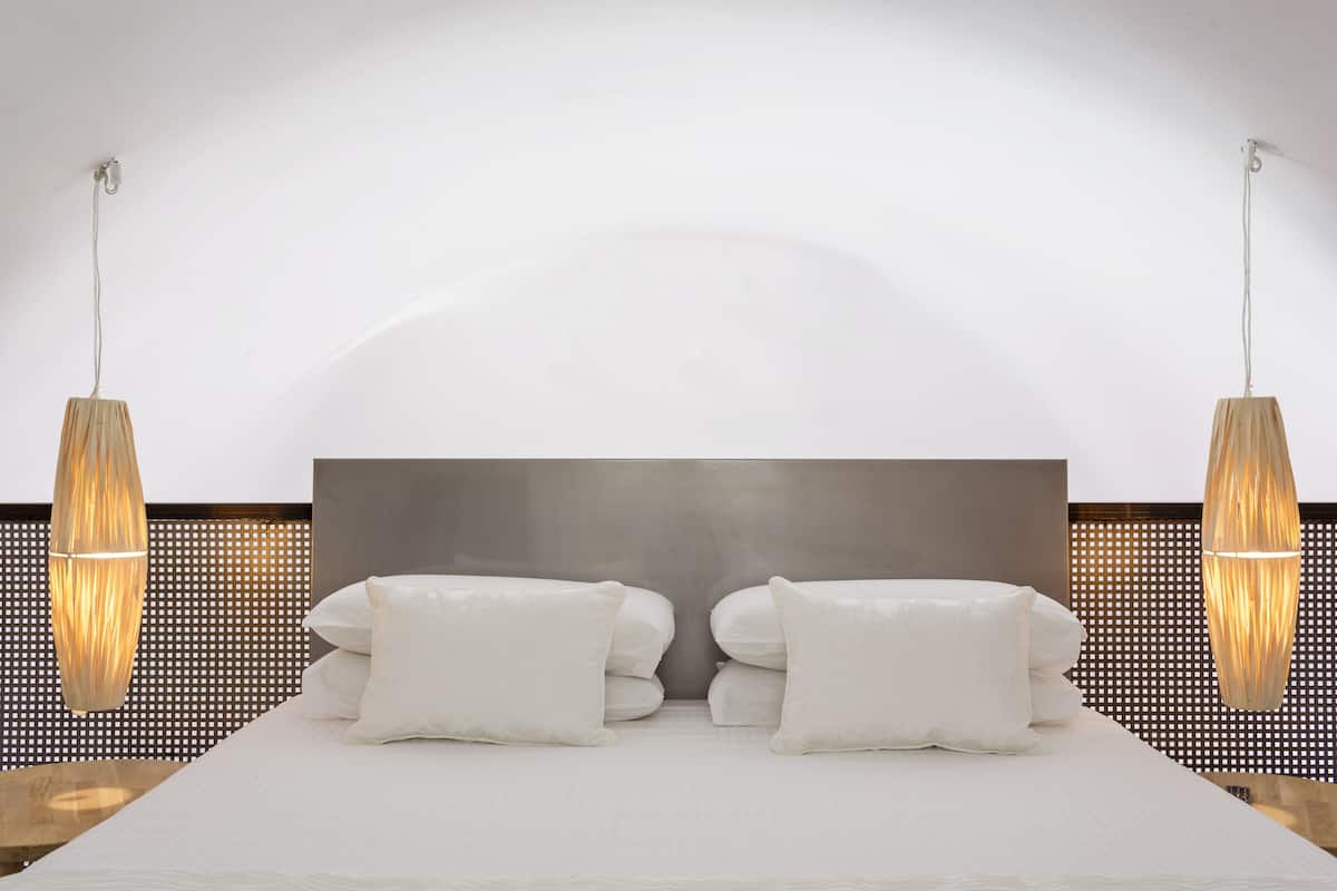 Une chambre d’hôtel moderne avec un grand lit, deux lampes de chevet et une décoration aux couleurs neutres.