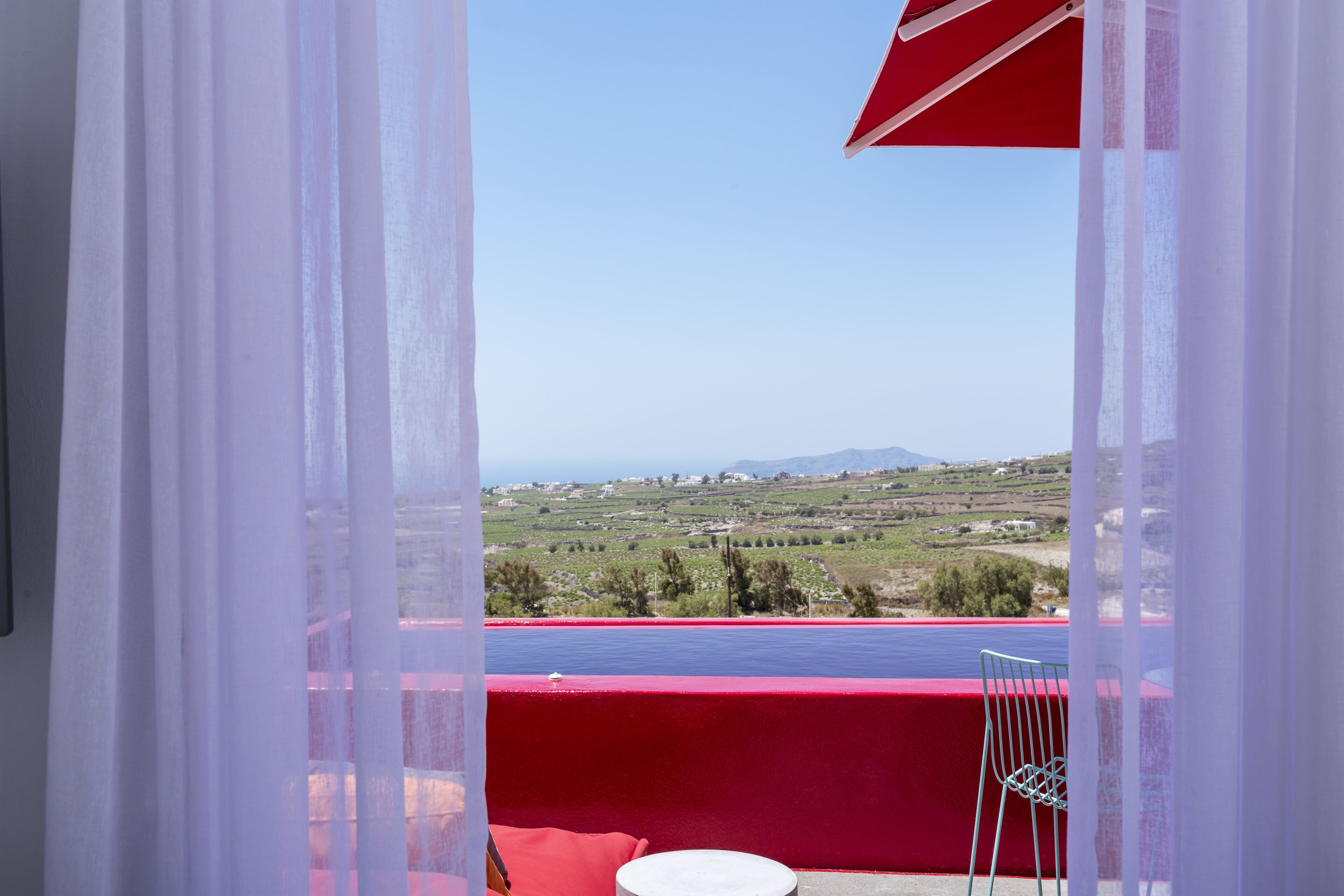 A balcony with a red railing and a view of a landscape.