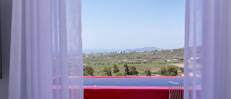 A balcony with a red railing and a view of a landscape.