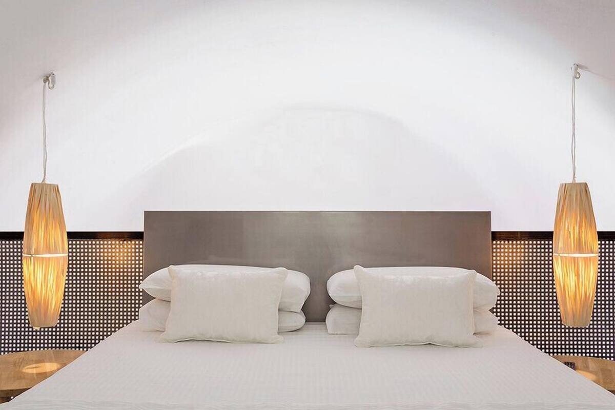 Une chambre d’hôtel moderne avec un grand lit, deux lampes de chevet et une grande tête de lit fixée au mur.