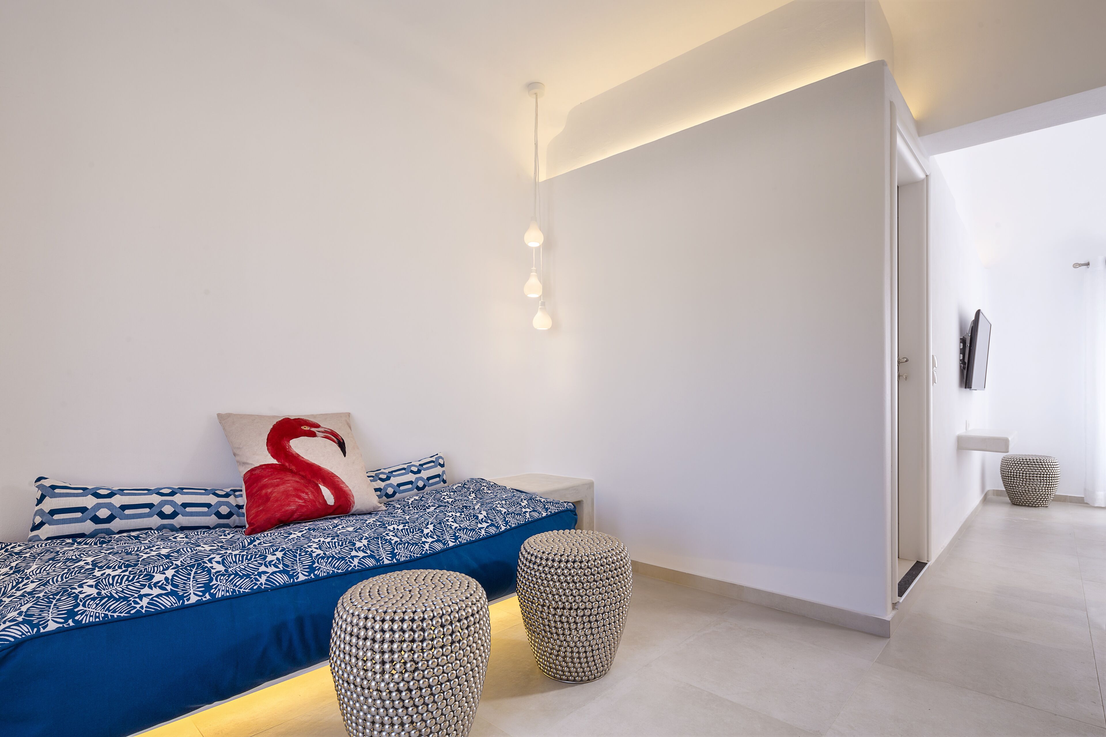 Une chambre à coucher moderne avec un lit, des coussins décoratifs et deux poufs ronds.