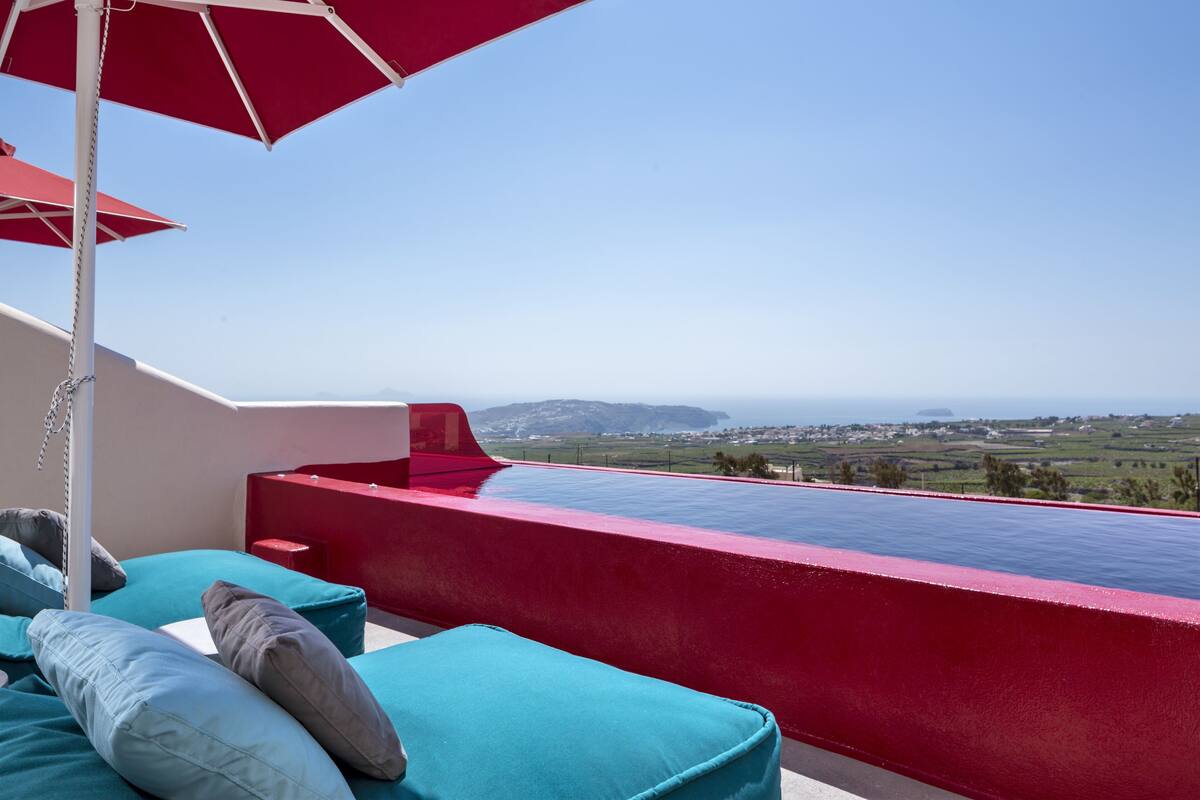 Une piscine à débordement rouge offrant une vue dégagée sur le paysage.