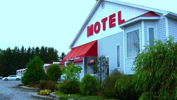 Ett motell med ett framträdande, rött solskydd och en stor skylt med texten ”MOTEL”.