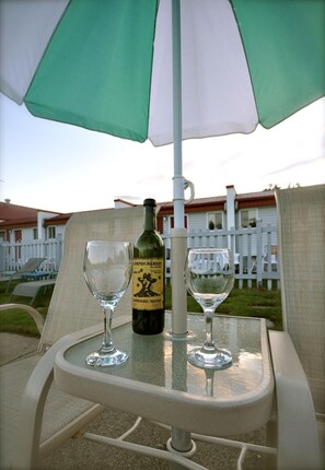 A table with two wine glasses and a bottle of wine under a green and white umbrella. - Motel de la Pente Douce (Magog)