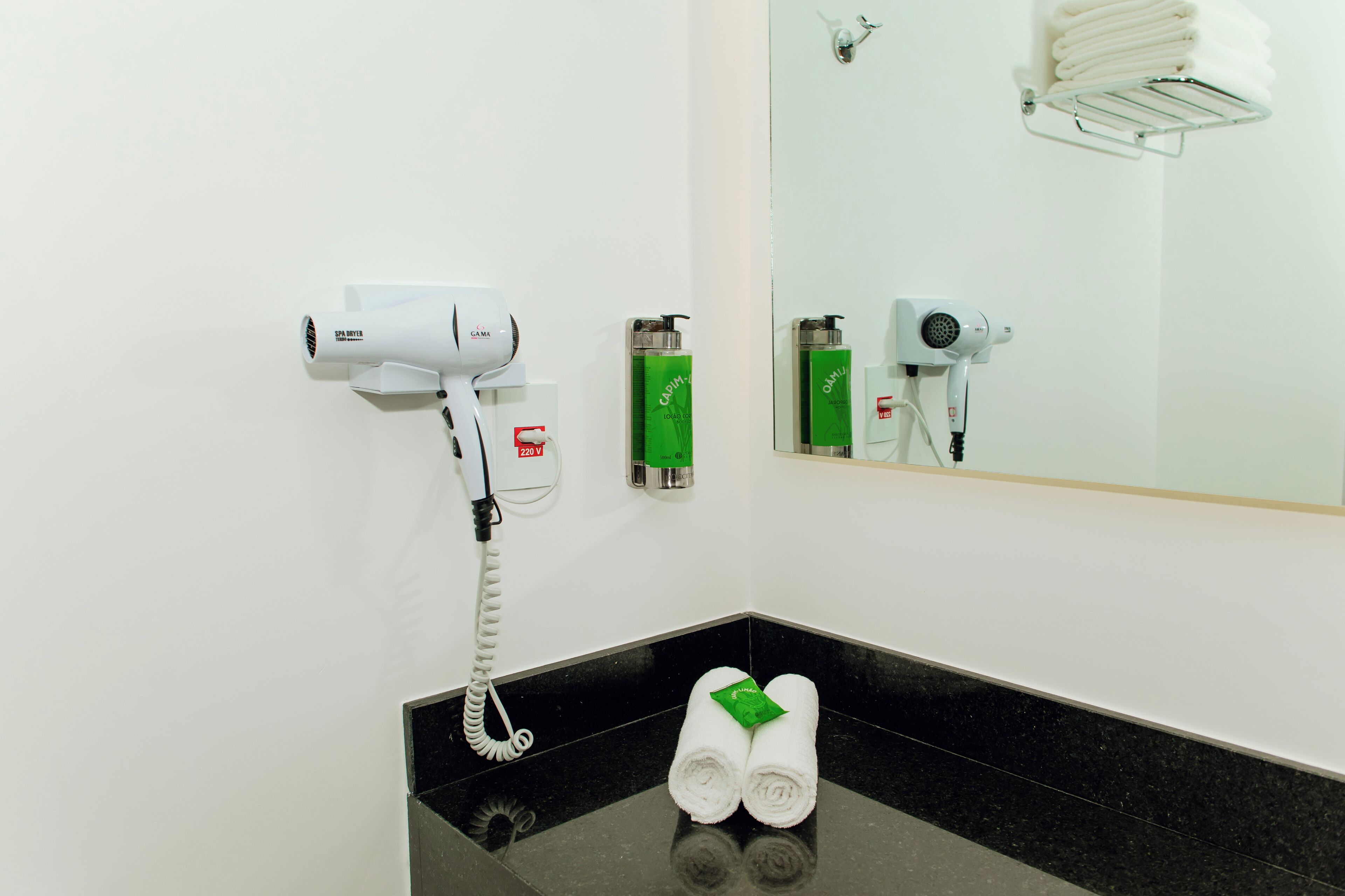 Une salle de bain équipée d’un sèche-cheveux, d’un porte-serviettes et d’un miroir.