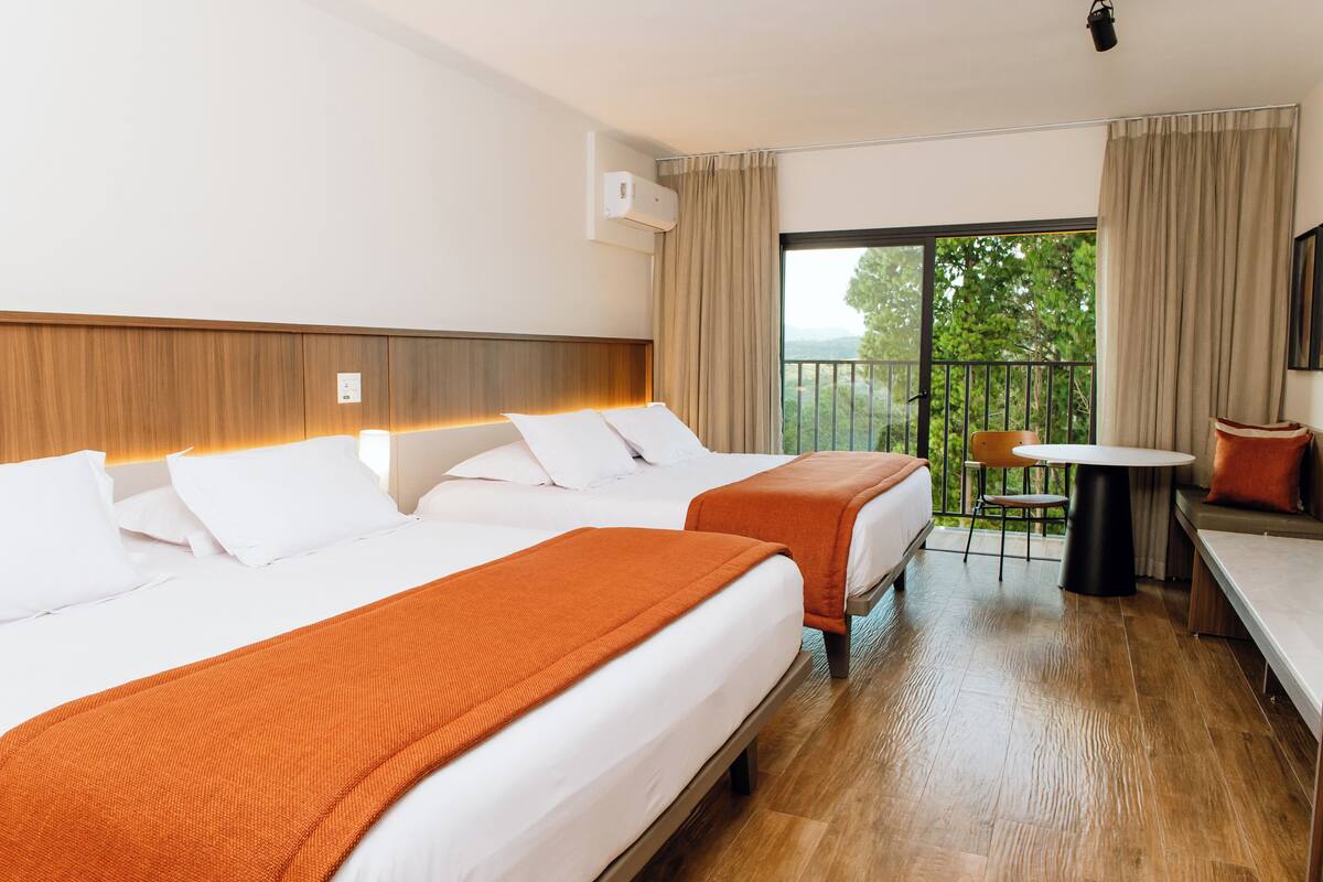 Ein Hotelzimmer mit zwei Betten, einem Balkon, einem kleinen Tisch und einem Stuhl.