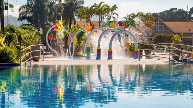 Una piscina con coloridas fuentes y una vista despejada del follaje circundante.