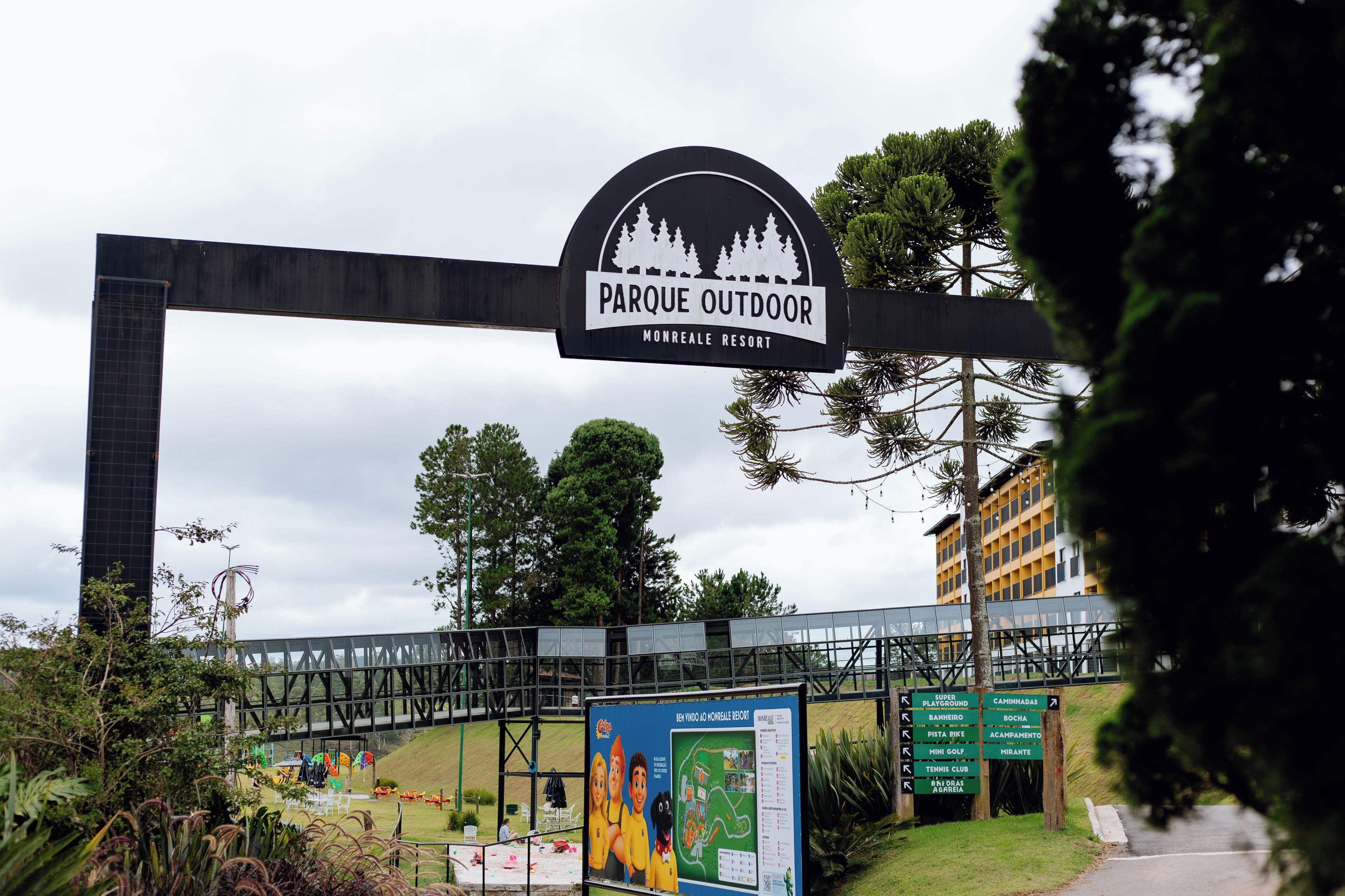 A sign for 'Parque Outdoor Monreale Resort' with a bridge and greenery in the background.