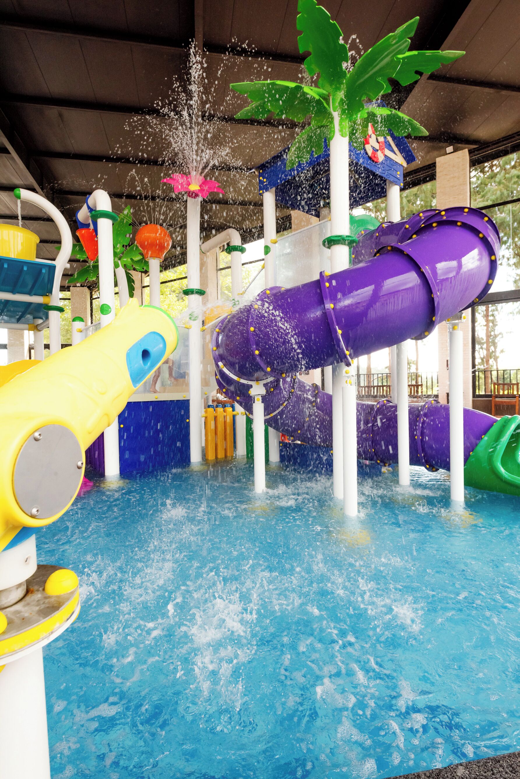 Ein Wasserspielbereich mit mehreren Rutschen und Wasserstrahlen, umgeben von einem Schwimmbecken.