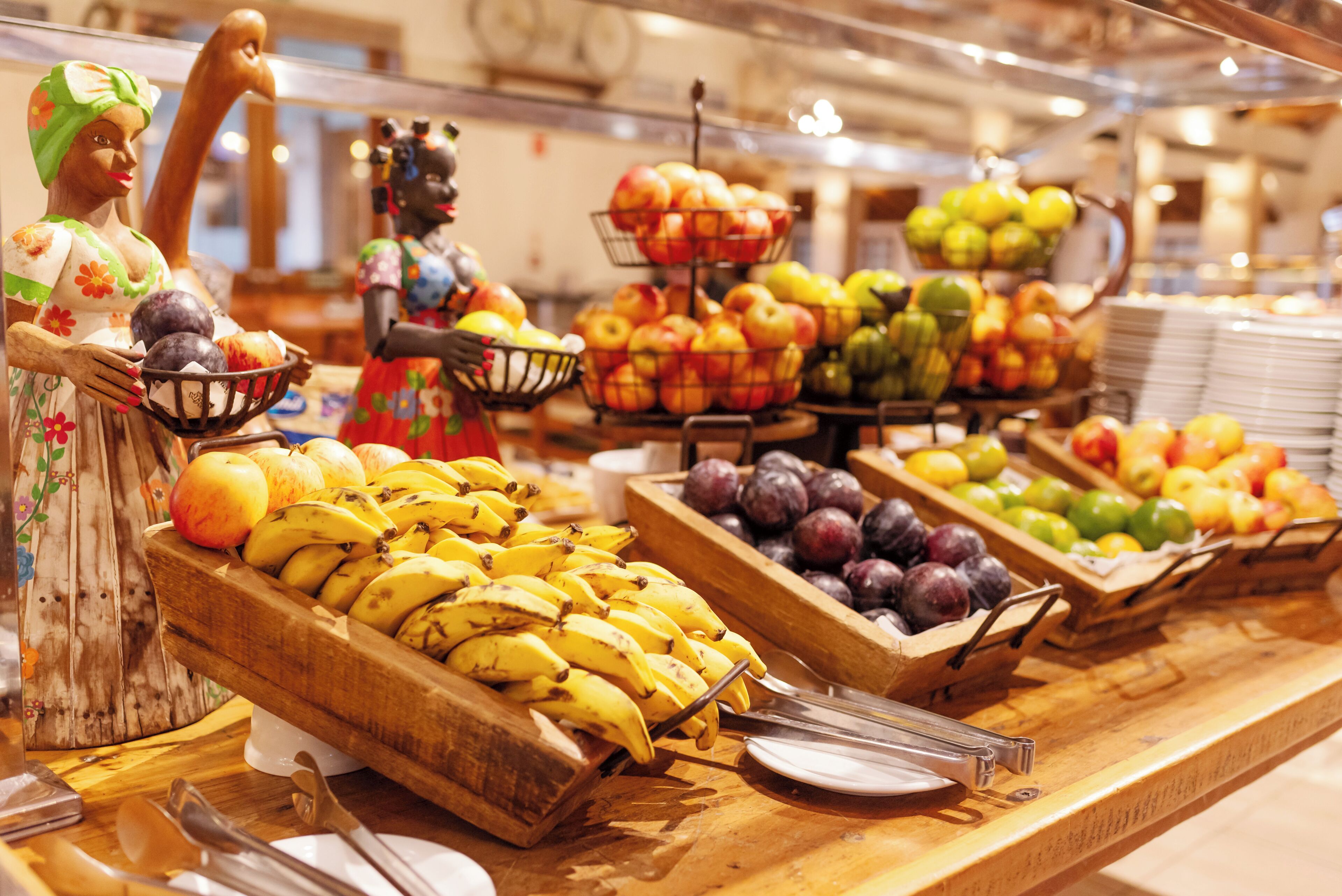 Un buffet proposant une variété de fruits et de légumes, notamment des bananes, des pommes et des prunes.